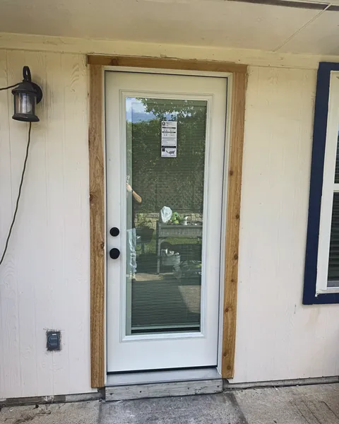 White full-lite patio door with cedar trim on white siding