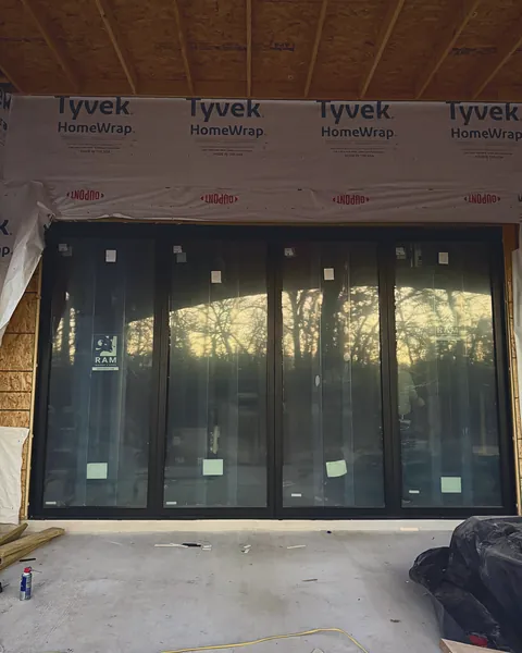 Custom four-panel black-framed door, with every panel operable, installed in a newly framed wall opening