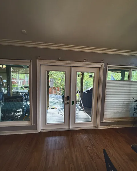 White full-glass French doors opening from a living room to a sunroom