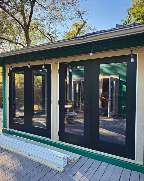 Two sets of black-framed French doors opening a sunroom to the deck
