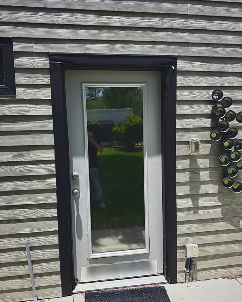 Black-framed full-lite door on gray lap siding