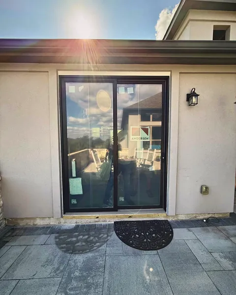 Black-framed sliding glass patio door on a stucco home