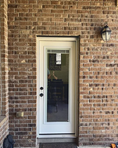 White full-lite glass back door installed in a brick wall