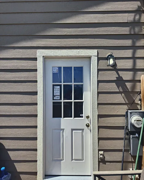 White half-lite side entry door with new trim on lap siding