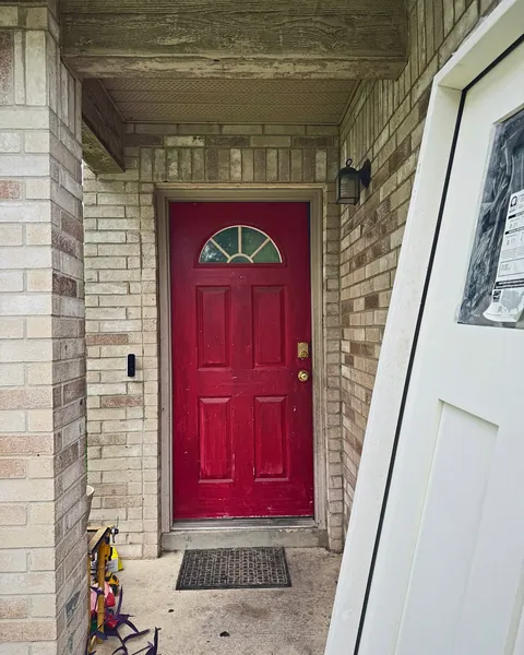 Red fiberglass front door with half-moon glass in a brick entry