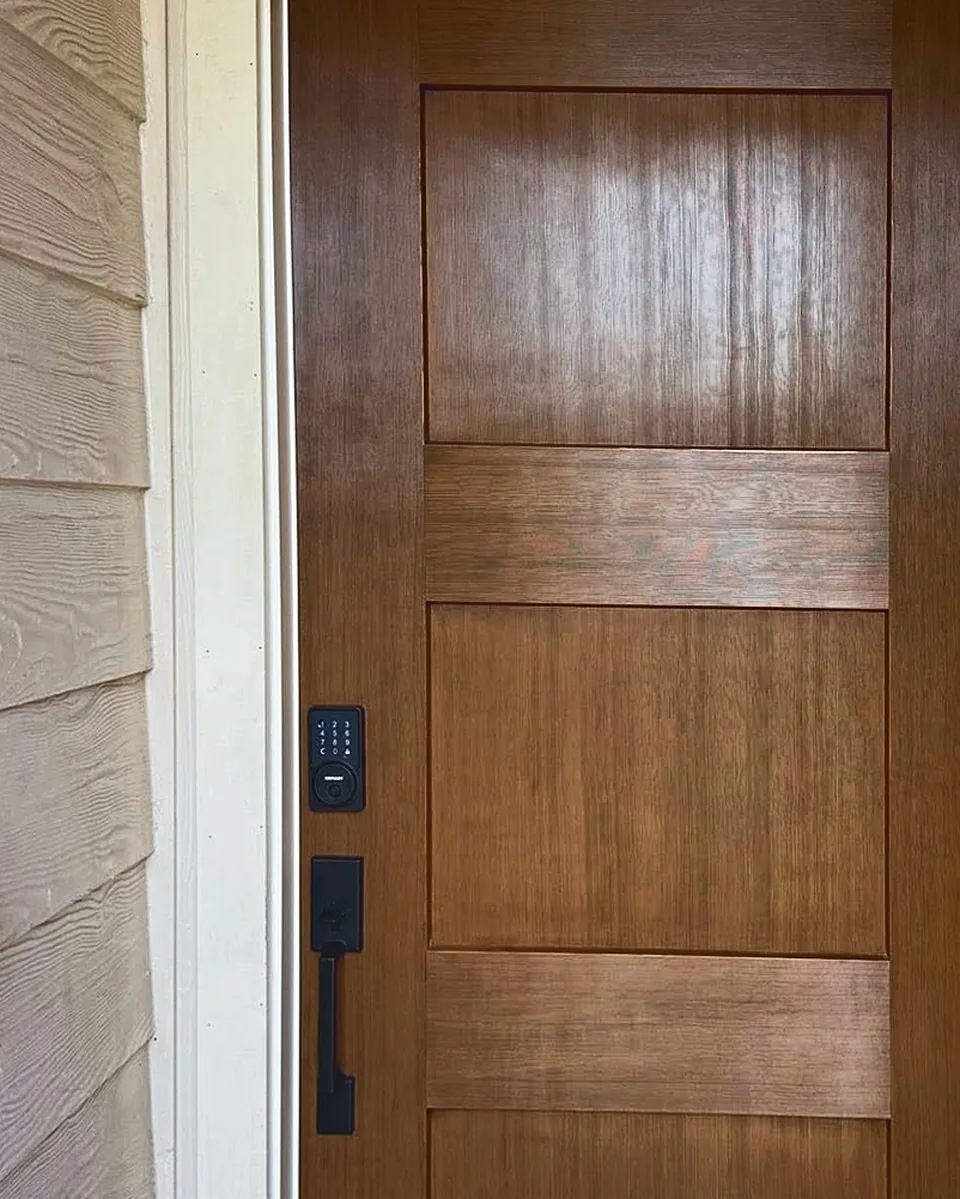 Close-up of a stained Shaker entry door with matte black smart lock and a tight, even reveal to the trim