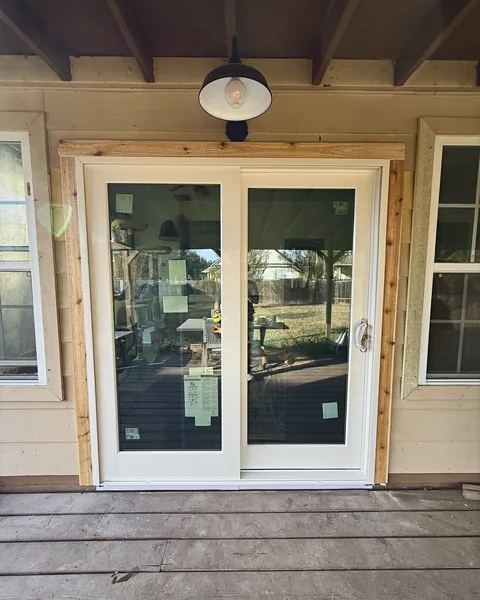 New white sliding patio door framed in natural cedar trim on a covered porch