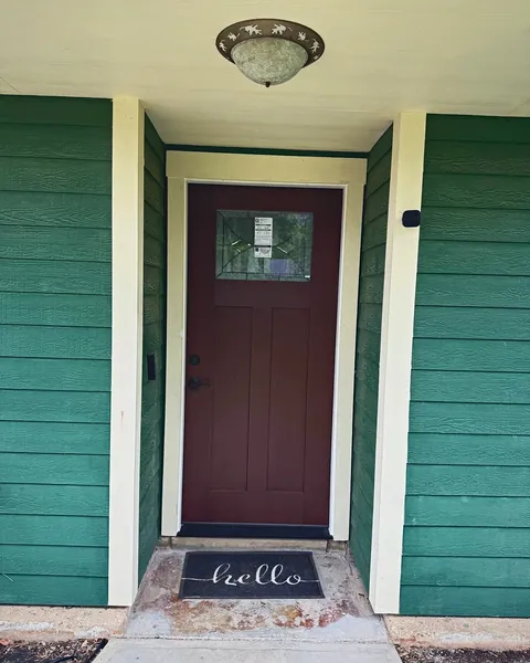 Dark stained Craftsman entry door with glass lite on a green-sided home