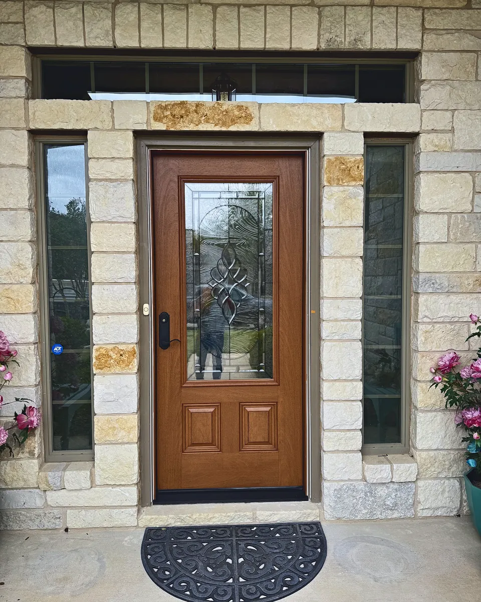 Stained wood entry door with leaded glass, sidelights and transom in a limestone surround