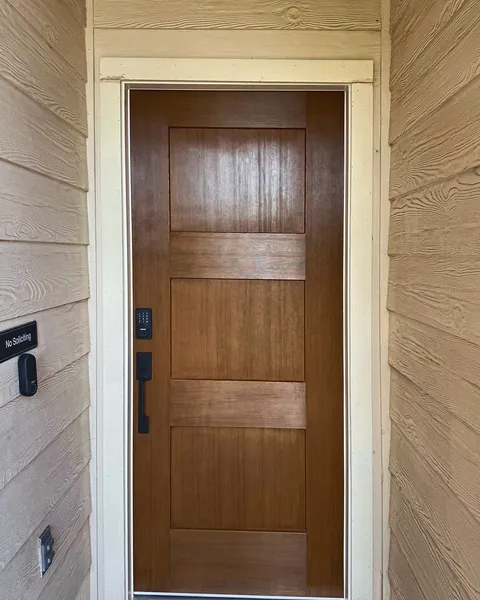 Stained wood Shaker-style entry door with matte black smart lock